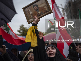 A veiled Iranian protester mourns while holding a framed portrait of Lebanon's Hezbollah Secretary General, Hassan Nasrallah, during a prote...