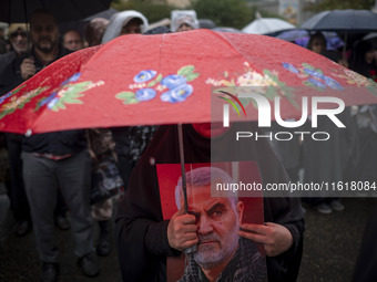 A veiled Iranian protester holds a portrait of the former commander of the Islamic Revolutionary Guard Corps' (IRGC) Quds Force, General Qas...