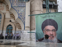 A man adjusts a billboard featuring a portrait of Lebanon's Hezbollah Secretary General, Hassan Nasrallah, during a protest gathering to con...