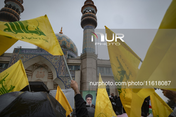 Iranian protesters wave Lebanon's Hezbollah flags next to a portrait of Hezbollah Secretary General, Hassan Nasrallah, during a protest gath...