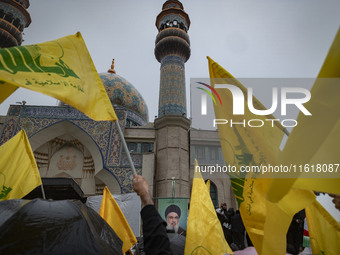 Iranian protesters wave Lebanon's Hezbollah flags next to a portrait of Hezbollah Secretary General, Hassan Nasrallah, during a protest gath...