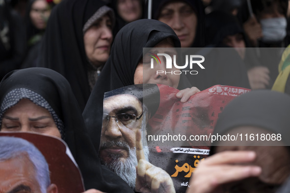 A veiled Iranian protester mourns while holding a portrait of Lebanon's Hezbollah Secretary General, Hassan Nasrallah, during a protest gath...