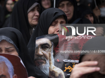 A veiled Iranian protester mourns while holding a portrait of Lebanon's Hezbollah Secretary General, Hassan Nasrallah, during a protest gath...