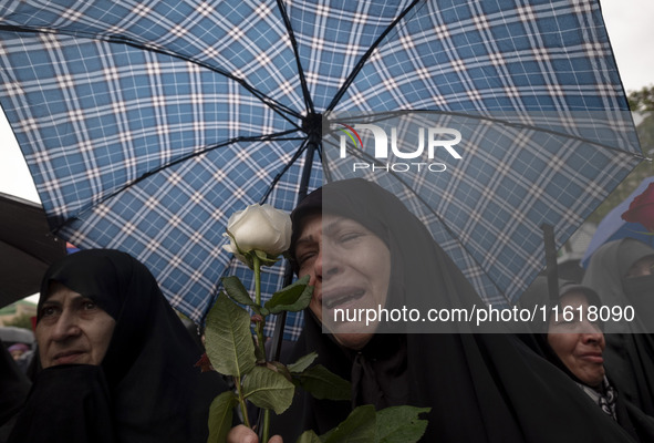 A veiled Iranian protester mourns while holding a flower during a protest gathering to condemn an Israeli air strike against Hezbollah's hea...