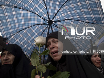 A veiled Iranian protester mourns while holding a flower during a protest gathering to condemn an Israeli air strike against Hezbollah's hea...