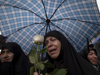 A veiled Iranian protester mourns while holding a flower during a protest gathering to condemn an Israeli air strike against Hezbollah's hea...