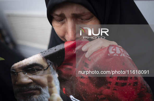 A veiled Iranian protester mourns while holding a portrait of Lebanon's Hezbollah Secretary General, Hassan Nasrallah, during a protest gath...