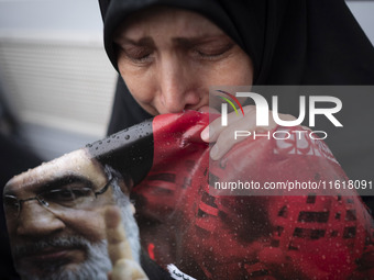 A veiled Iranian protester mourns while holding a portrait of Lebanon's Hezbollah Secretary General, Hassan Nasrallah, during a protest gath...