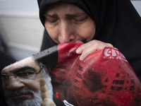 A veiled Iranian protester mourns while holding a portrait of Lebanon's Hezbollah Secretary General, Hassan Nasrallah, during a protest gath...