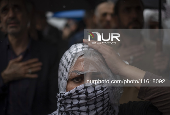 An Iranian woman wearing a Palestinian scarf beats herself while taking part in a protest gathering to condemn an Israeli air strike against...