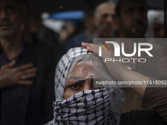 An Iranian woman wearing a Palestinian scarf beats herself while taking part in a protest gathering to condemn an Israeli air strike against...