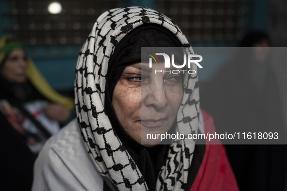 An Iranian woman wearing a Palestinian scarf mourns while taking part in a protest gathering to condemn an Israeli air strike against Hezbol...