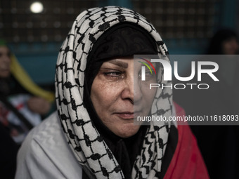 An Iranian woman wearing a Palestinian scarf mourns while taking part in a protest gathering to condemn an Israeli air strike against Hezbol...