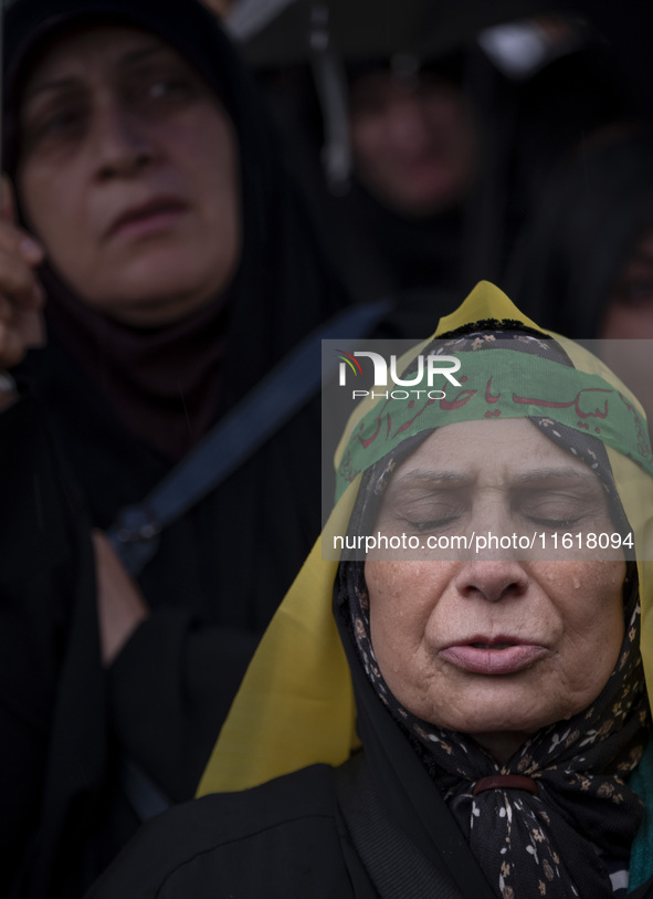 An Iranian woman wearing a headband with Persian script that reads ''Yes Khamenei'' mourns while taking part in a protest gathering to conde...