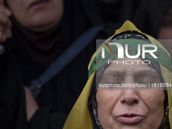 An Iranian woman wearing a headband with Persian script that reads ''Yes Khamenei'' mourns while taking part in a protest gathering to conde...