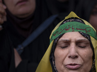 An Iranian woman wearing a headband with Persian script that reads ''Yes Khamenei'' mourns while taking part in a protest gathering to conde...