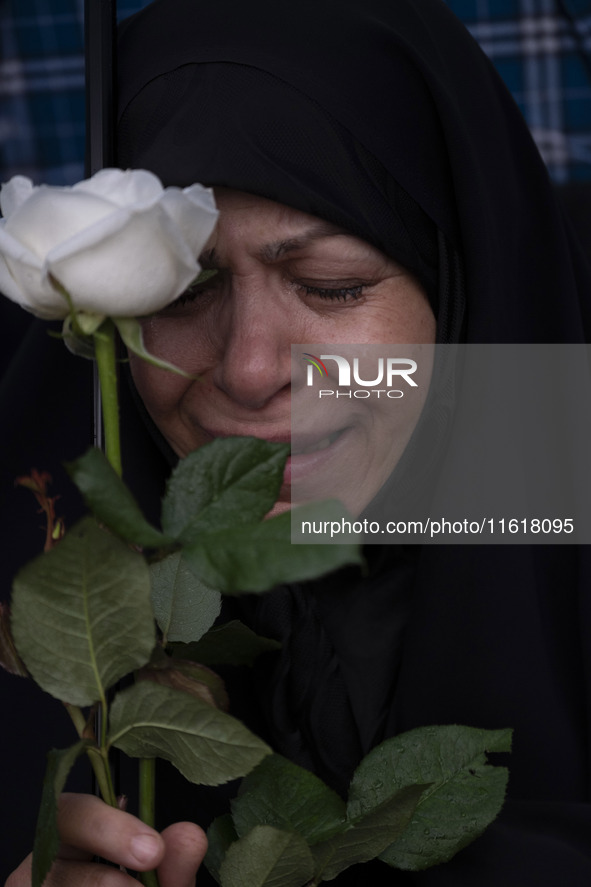 A veiled Iranian protester mourns while holding a flower during a protest gathering to condemn an Israeli air strike against Hezbollah's hea...