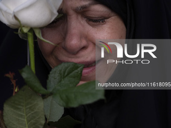 A veiled Iranian protester mourns while holding a flower during a protest gathering to condemn an Israeli air strike against Hezbollah's hea...