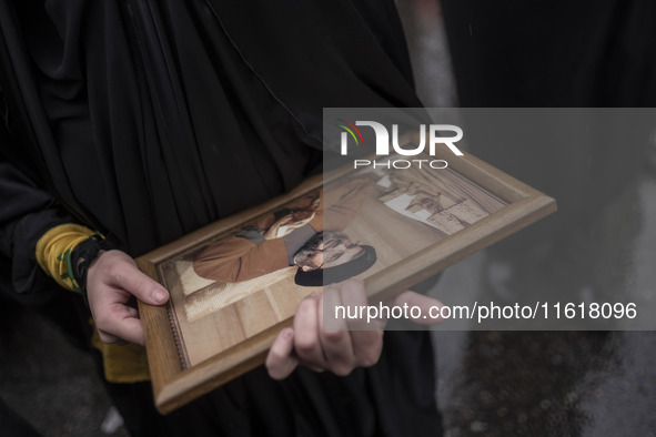 A veiled Iranian protester holds a framed portrait of Lebanon's Hezbollah Secretary General, Hassan Nasrallah, during a protest gathering to...