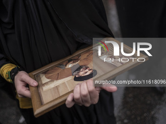 A veiled Iranian protester holds a framed portrait of Lebanon's Hezbollah Secretary General, Hassan Nasrallah, during a protest gathering to...