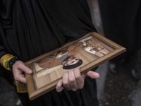 A veiled Iranian protester holds a framed portrait of Lebanon's Hezbollah Secretary General, Hassan Nasrallah, during a protest gathering to...