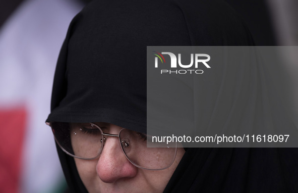 A veiled Iranian woman mourns while taking part in a protest gathering to condemn an Israeli air strike against Hezbollah's headquarters in...