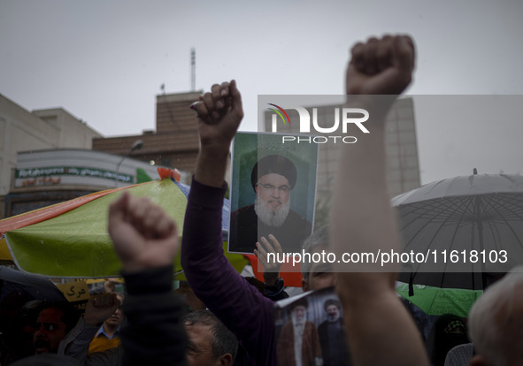 An Iranian protester holds up a portrait of Lebanon's Hezbollah Secretary General, Hassan Nasrallah, during a protest gathering to condemn a...