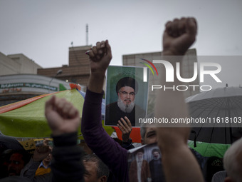 An Iranian protester holds up a portrait of Lebanon's Hezbollah Secretary General, Hassan Nasrallah, during a protest gathering to condemn a...