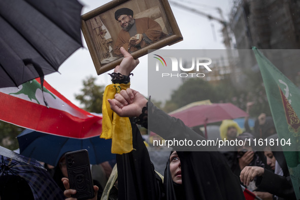 A veiled Iranian protester shouts anti-Israeli and anti-U.S. slogans while holding a framed portrait of Lebanon's Hezbollah Secretary Genera...