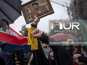 A veiled Iranian protester shouts anti-Israeli and anti-U.S. slogans while holding a framed portrait of Lebanon's Hezbollah Secretary Genera...