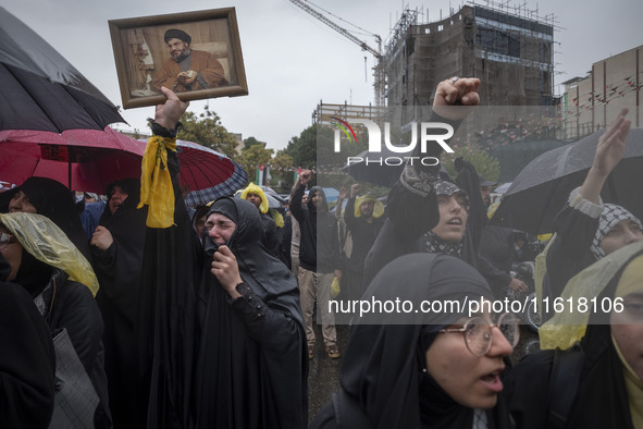 A veiled Iranian protester holds up a framed portrait of Lebanon's Hezbollah Secretary General, Hassan Nasrallah, who was killed in an Israe...