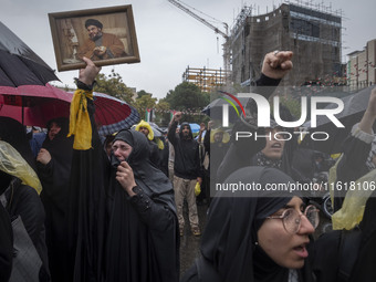 A veiled Iranian protester holds up a framed portrait of Lebanon's Hezbollah Secretary General, Hassan Nasrallah, who was killed in an Israe...