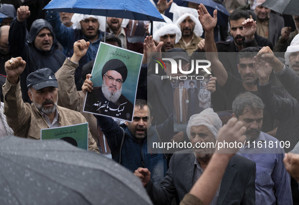 An Iranian protester holds up a portrait of Lebanon's Hezbollah Secretary General, Hassan Nasrallah, during a protest gathering to condemn a...