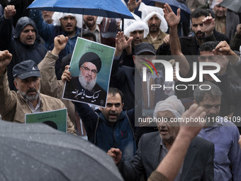 An Iranian protester holds up a portrait of Lebanon's Hezbollah Secretary General, Hassan Nasrallah, during a protest gathering to condemn a...