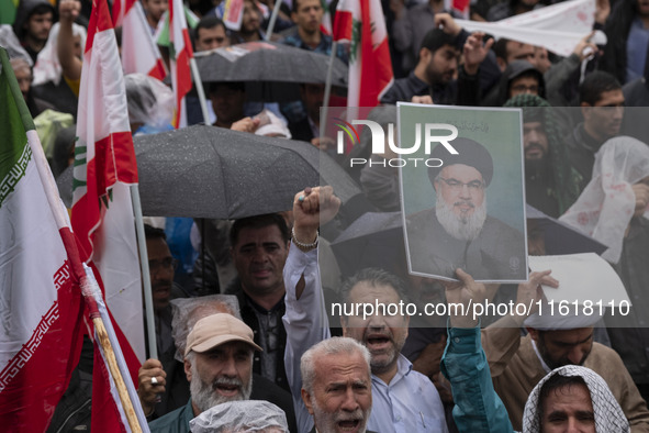 An Iranian protester holds up a portrait of Lebanon's Hezbollah Secretary General, Hassan Nasrallah, during a protest gathering to condemn a...