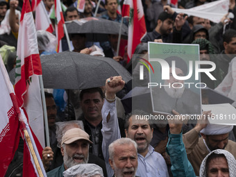 An Iranian protester holds up a portrait of Lebanon's Hezbollah Secretary General, Hassan Nasrallah, during a protest gathering to condemn a...