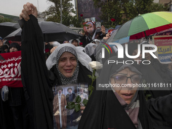 A veiled Iranian protester shouts anti-Israeli and anti-U.S. slogans while holding a poster featuring portraits of the former commander of t...