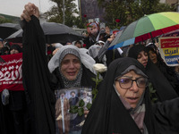 A veiled Iranian protester shouts anti-Israeli and anti-U.S. slogans while holding a poster featuring portraits of the former commander of t...