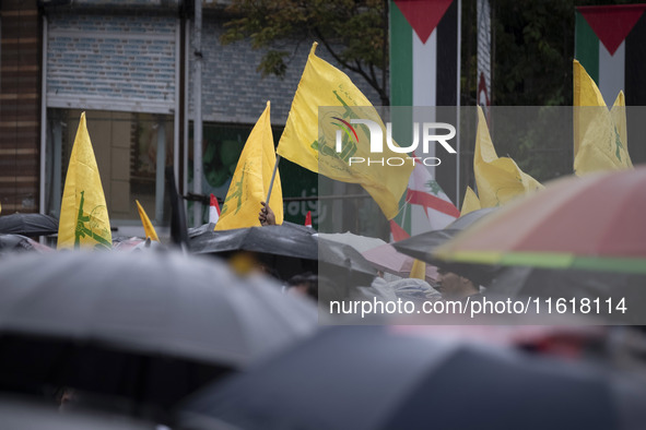 Iranian protesters wave Lebanon's Hezbollah flags during a protest gathering to condemn an Israeli air strike against Hezbollah's headquarte...