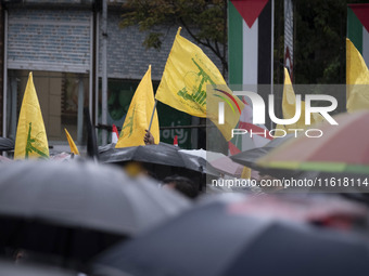 Iranian protesters wave Lebanon's Hezbollah flags during a protest gathering to condemn an Israeli air strike against Hezbollah's headquarte...