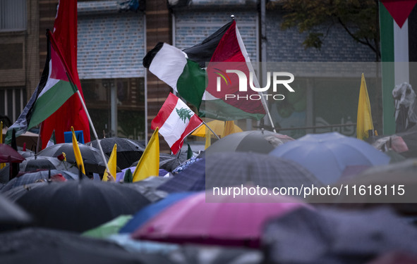 Iranian protesters wave Palestinian flags and a Lebanese flag during a protest gathering to condemn an Israeli air strike against Hezbollah'...