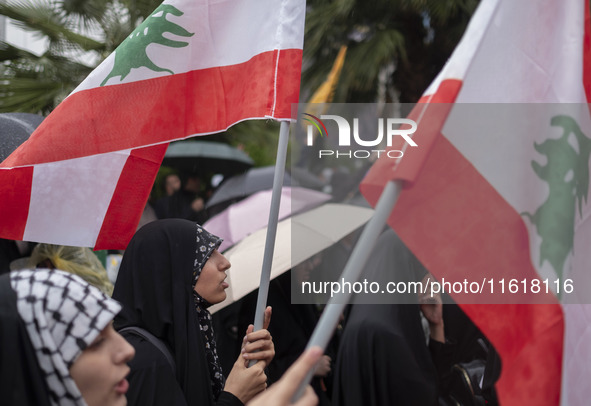 Veiled protesters wave Lebanese flags during a protest gathering to condemn an Israeli air strike against Hezbollah's headquarters in the su...