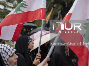 Veiled protesters wave Lebanese flags during a protest gathering to condemn an Israeli air strike against Hezbollah's headquarters in the su...