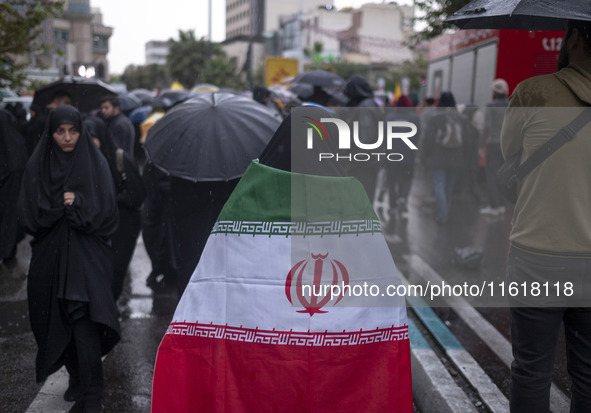 A veiled Iranian protester wears an Iranian flag while taking part in a protest gathering to condemn an Israeli air strike against Hezbollah...