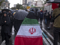 A veiled Iranian protester wears an Iranian flag while taking part in a protest gathering to condemn an Israeli air strike against Hezbollah...