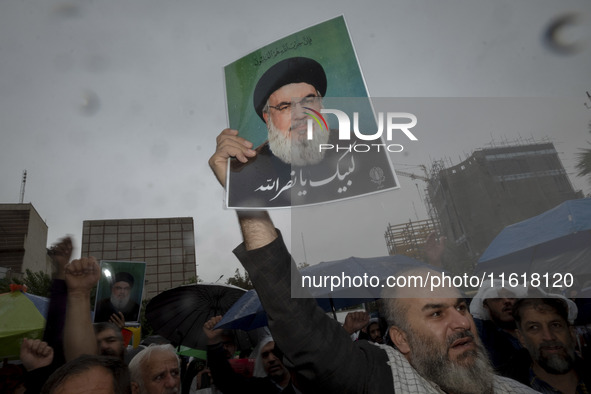 An Iranian protester holds up a portrait of Lebanon's Hezbollah Secretary General, Hassan Nasrallah, during a protest gathering to condemn a...