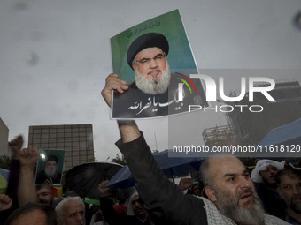 An Iranian protester holds up a portrait of Lebanon's Hezbollah Secretary General, Hassan Nasrallah, during a protest gathering to condemn a...