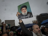 An Iranian protester holds up a portrait of Lebanon's Hezbollah Secretary General, Hassan Nasrallah, during a protest gathering to condemn a...