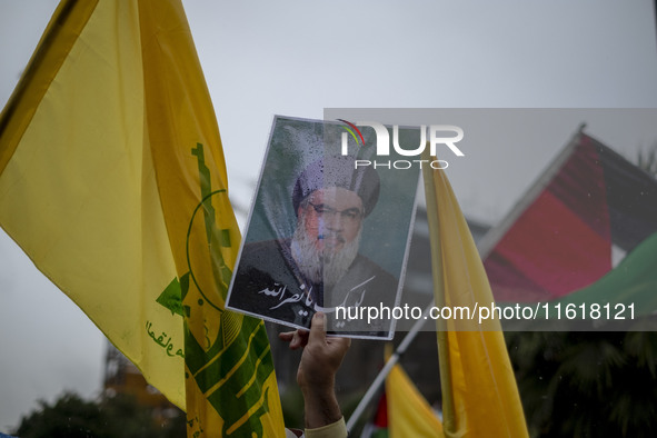 An Iranian protester holds up a portrait of Lebanon's Hezbollah Secretary General, Hassan Nasrallah, during a protest gathering to condemn a...