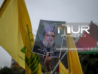 An Iranian protester holds up a portrait of Lebanon's Hezbollah Secretary General, Hassan Nasrallah, during a protest gathering to condemn a...